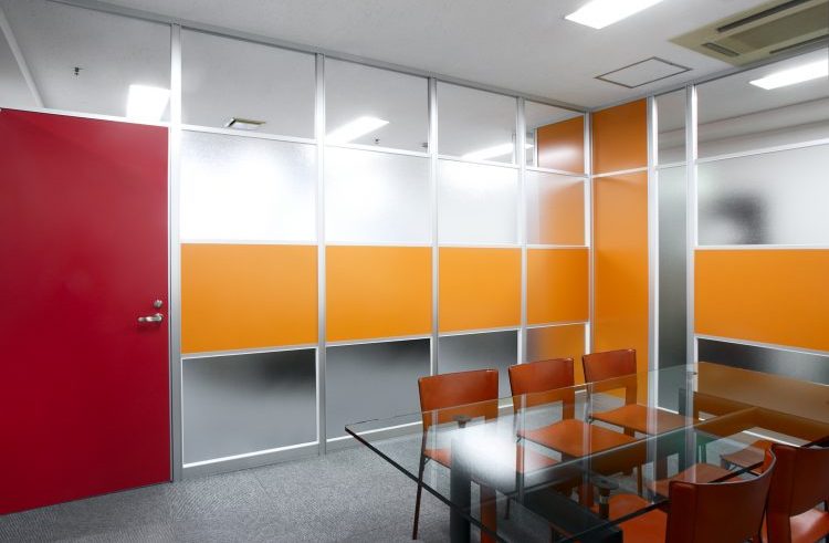 アルミ素材のオレンジ色のパーティションと赤いドアとガラスのパーティションを使った会議室の事例
